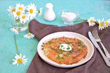 Wall Mural - Roshty, fried potato pancake from boiled potatoes on a white clay plate on a turquoise background. Served with sour cream. Swiss cuisine.