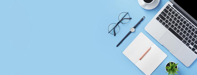 Girl write on open white book or accounting on a minimal clean light blue desk with laptop and accessories, copy space, flat lay, top view, mock up