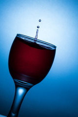 glass of wine with splash  on blue background