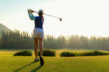 Healthy Sport. Asian Sporty Woman Golfer Player Doing Golf Swing Tee Off On The Green Evening Time, She Presumably Does Exercise.  Healthy Lifestyle Concept.