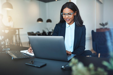 Wall Mural - Smiling young African American businesswoman working in a modern