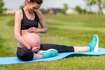 Poster - Pregnant woman fitness exercises on grass at sunny day