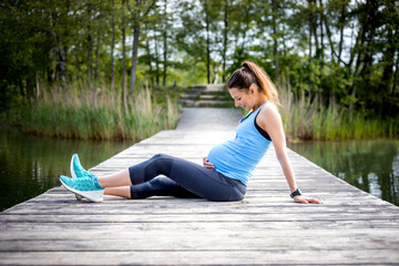 Wall Mural - Pregnant woman exercising outdoor and resting