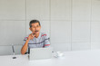 © otello-stpdc - Asian Senior businessman, Thinking something. front on the desk. there are white coffee mug and laptop computer, in the office room.