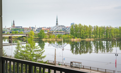 Panoramic view of Riga city covered in clouds. Iconic railroad bridge and old town panorama across the river  Daugava. Picturesque scenery of historical architecture.