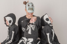 Happy Friendly Family Of Musicians In Carnival Costumes, Boys And Young Mother Play Together. Black Suit With Image Of Skeletons. Classic Halloween Costume. Funny Children