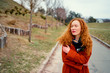 © Loginova - Autumn season. Beautiful yong woman with long red hair wearing coat in park.