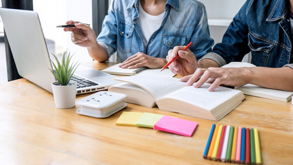 Wall Mural - high school tutor or college student group sitting at desk in library studying and reading, doing ho