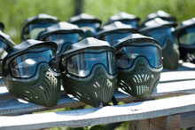 Special Protective Mask For Playing Paintball With Traces And Spot Of Hit Of A Ball With Paint. Equipment For Playing Paintball On A Wooden Table