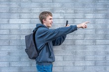 Teenager Pointing To Something He Is Recording With His Cellphone.