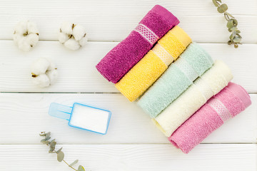 powder for laundry and cotton towels on white wooden background top view