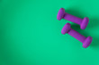 © Jaimie - Fitness equipment with womens purple weights/ dumbbells isolated on a teal green background with copyspace