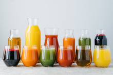 Multicolored Fruit Juice In Glass Jars Isolated Over White Background. Drinks Containing Vitamins Made Of Orange, Pomegranate, Carrot, Spinach