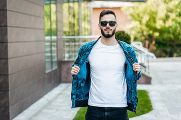 Sticker - A young stylish man with a beard in a white T-shirt and glasses. Street photo