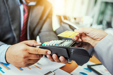 Hand of business man customer paying with NFC technology contactless credit card.