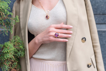 People, fashion, jewelry and luxury concept, closeup of woman wearing luxury jewelry standing on the street. Color gemstone ring and pendant with colored diamonds and gemstones