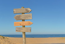 Wooden Signs On A Post In A Beach Under Blue Sky
