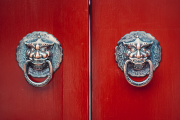 Canvas Print - Lion doorknockers on a red door of traditional siheyuan - charactaristic courtayrd of traditional hutong residential area in Beijing, capital city of China