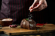 © Anton - Chef hands cooking meat steak and adding salt and pepper on black copy space background for menu restaurant or recipe text.