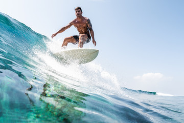 Wall Mural - Young hispanic man surfs the glassy ocean wave at sunny day