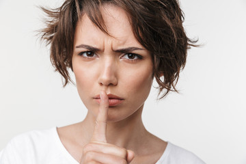 Canvas Print - Beautiful young pretty displeased sad woman posing isolated over white wall background showing silence gesture.