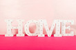 Word HOME from the wooden decorative letters on pink background