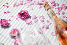 Bottle Of Pink Sparkling Wine And Glass On A White Background With Pink Roses