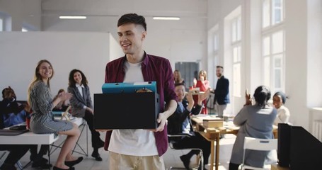 Wall Mural - Happy young Caucasian male office employee walks into new multiethnic office hired on a new job, colleagues welcome him.