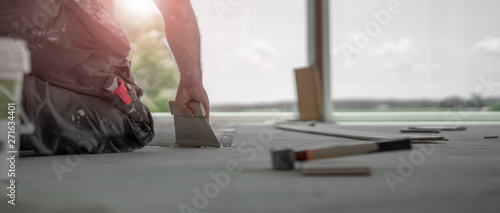 Cuadros en Lienzo Handwerker verteilt den Parkettkleber mit der Kleberspachtel auf dem frischen Es