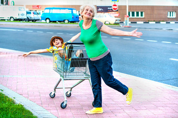 Wall Mural - A cheerful, fashionable grandmother rolls her happy grandson in