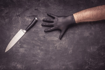 Male Hands with Black Latex Gloves and Knife on Dark Background