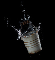 Sticker - Metal bucket with water splash or explosion flying in the air isolated on black background,Motion blur