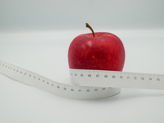 Red apple and measure tape centimeter that represent reduce weight or diet food and exercise for body good shape design concept isolated on white background