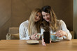© Alvaro Hernandez/ADDICTIVE STOCK - Two stylish female friends with cups of fresh coffee smiling and posing for selfie while sitting at table in cozy restaurant