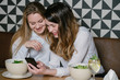 © Alvaro Hernandez/ADDICTIVE STOCK - Elegant women friends using phone while sitting at table of restaurant during lunch