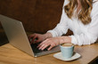 © Alvaro Hernandez/ADDICTIVE STOCK - Crop view of anonymous female freelancer browsing modern laptop while sitting at table with a cup of coffee in cozy restaurant