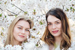 © Alvaro Hernandez/ADDICTIVE STOCK - Two dreamy young women near trees with white flowers on sunny day in park