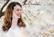 © Alvaro Hernandez/ADDICTIVE STOCK - Young woman smiling and talking over the phone near trees with white flowers on sunny day in park