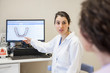 © David Fuentes/ADDICTIVE STOCK - Young female stomatologist in medical gown sitting on chair and showing patient teeth on computer in dentistry