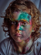 Cute Funny Boy Painted In Bright Paints Sitting Near Curtains And Drawing On Face