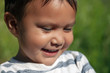 © mmg1design - The cute face of a hispanic young boy smiling and looking thoughtful at something on a sunny day.