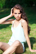 © Andrey_Arkusha - Young brunette woman in a turquoise blouse posing sitting on a green lawn in a summer park