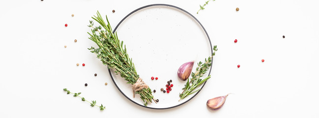 Empty plate with greens herbs and spices around