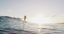 Young smiling woman surfing a wave in slow motion, walking with style on her longboard riding summer wave at sunset, surfing lifestyle stoke
