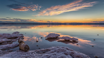 Wall Mural - A tree trunk lies in the salt lake. The lagoon of Torrevieja in Spain after sunset with beautiful reflections in the water. The salt forms interesting shapes, like a mushroom.