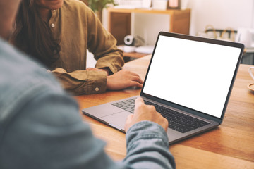 People using and looking at mockup laptop computer on wooden table together