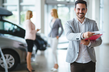 Handsome salesman at car dealership selling vehichles