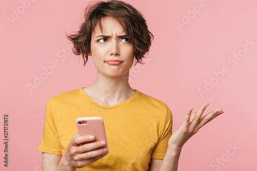 Cuadros en Lienzo Confused young beautiful woman posing isolated over pink wall background using mobile phone