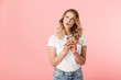 © Drobot Dean - Thinking young blonde woman posing isolated over pink wall background using mobile phone.