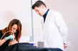 © GENETTICA - Doctor supervising facial treatment that the beautician is applying to the patient in an aesthetic medicine clinic.